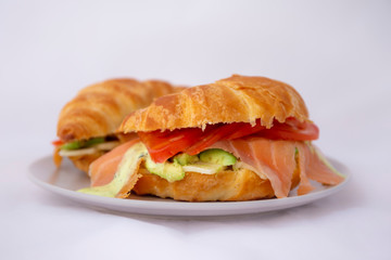 croissant sandwich of a salmon and avocado and the tomato