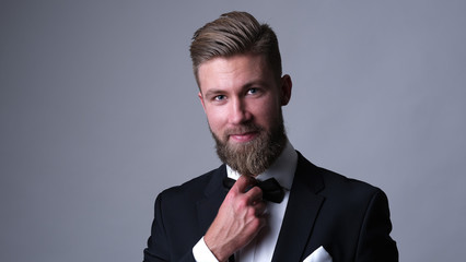 Handsome caucasian man with beard in classic black suit.