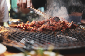 Hand grilling a Korean barbecue ribs meat with smoke