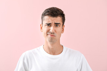 Displeased young shaved man on color background