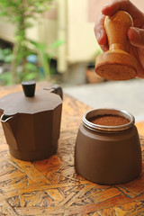 Man's Hand Tapping Ground Coffee with Wooden Tamper before Brewing