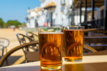 Cold amber color light spanish beer served in glass in outdoor cafe in town on sand, El Rocio in Andalusia, Spain