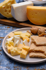 Tasty snacks, cheese blocks from Dutch yellow gouda and white goat hard cheeses and French holes cheese emmentaler