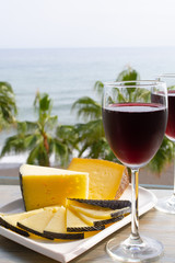 Red wine served in glasses with spanish cheese in lounge bar with sea view and palm trees