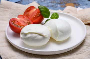 Cheese collection, organic mozzarella soft cheese served with ripe tomato and fresh green basil