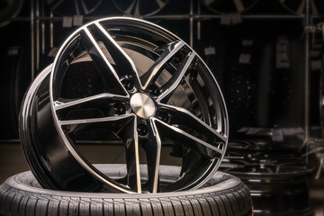 new expensive cast aluminum disc wheel black color, photographed on the tire. dark background,...