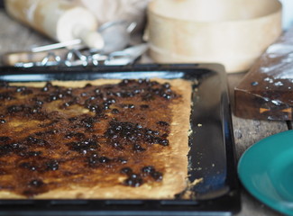 making roll cake confectionery with berry sent on a black baking sheet with ingredients on a brown rustic background