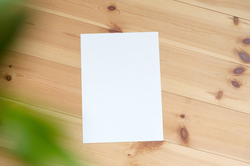 木製テーブルと緑のボケと白い紙の背景