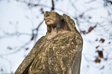 Monument and candles in the cemetery. All Saints Day in Poland. Stone statue. Statue without a face.