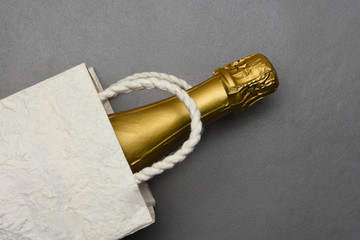 Champagne: Flat Lay Gift Bag with a bottle of sparkling wine on gray tile surface.