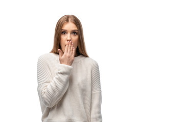 attractive shocked young woman in white sweater covering mouth, isolated on white