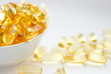Dietary supplementation. Capsules of fish oil in the white bowl, light background