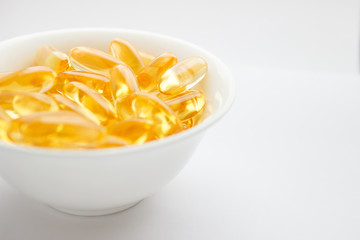 Dietary supplementation. Capsules of fish oil in the white bowl, light background