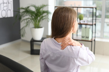 Young businesswoman suffering from back pain in office