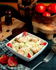 a bowl of chicken caesar salad with extra grated cheese