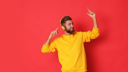 Young man in yellow blouse with headphones on listening a music.