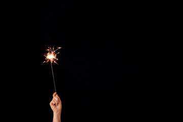 Female hand with Christmas sparkler on dark background