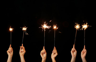 Female hands with Christmas sparklers on dark background