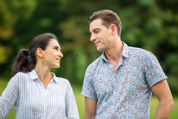 Obraz premium Outdoor shot of young couple in love joyful in the park through grass field. Man and woman hugging and Laugh on grass field.
