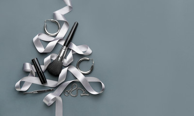 Beautiful Christmas tree made of makeup supplies, jewelry and ribbon on grey background