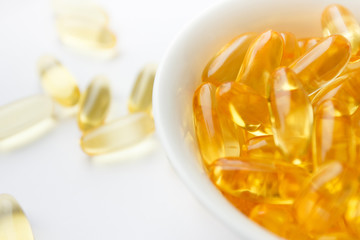 Dietary supplementation. Capsules of fish oil in the white bowl, light background
