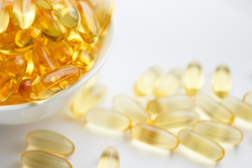 Dietary supplementation. Capsules of fish oil in the white bowl, light background