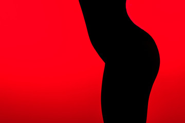 black silhouette of sexy buttocks of young woman, isolated on red