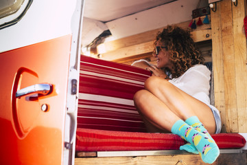 Travel concept with happy alternative people lifestyle - Beautiful attractive young caucasian woman sit down inside a red hand made wooden vintage van smiling and looking outside