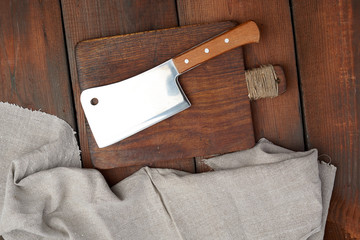 large steel sharp meat knife lies on a rectangular wooden brown board