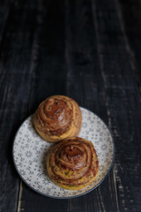 Cheese and dill bread buns on plate standing on black wooden background. Tasty unhealthy food. Diet, nutrition, eating habits concept. Place for text.  Vertical shot