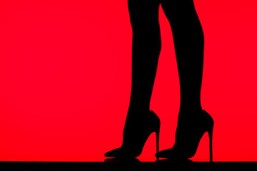 black silhouette of seductive girl in heels posing on table, isolated on red