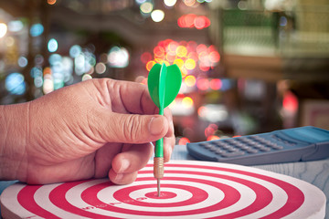 Dart arrow in hand on target dartboard ,Business success concept.