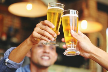Two young men colliding with two glass of beer to celebrate their success..
