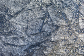Fototapeta na wymiar Thin ice on the pond, texture background backdrop wallpaper. An uneven rough layer of ice with frozen cracks. Winter snow cold ice