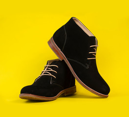 Man fashion black ankle boots leather isolated on yellow background.