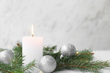 Glowing candle with Christmas decor on white background