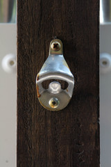 Old classic bottle opener on wooden pole.