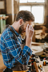 carpenter covering face while touching googles in workshop