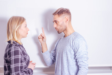 Violent argument of couple concept. Young man warns his wife with threatening gesture
