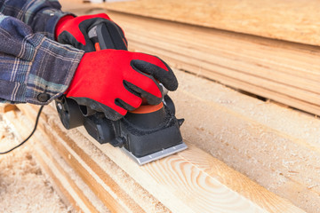 carpenter polishes boards with an electric jack planer at a private house construction site