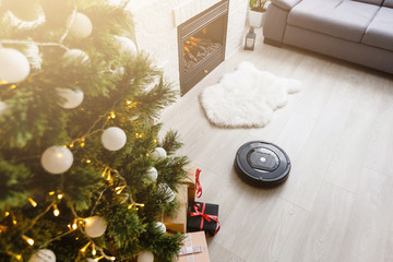 Robotic vacuum cleaner on laminate wood floor smart cleaning technology. Cristmas tree