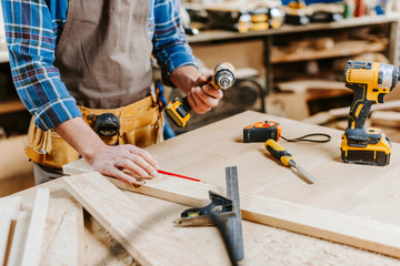 cropped view of carpenter holding hammer drill