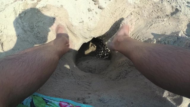 The man dig a hole in the sand.