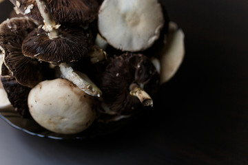 Raw champignons standing on black wooden table. Healthy organic vegetarian food. Diet, nutrition, eating habits concept. Copy space