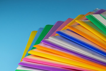 Multi-colored plastic folders for paper on a blue background.