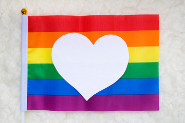 Gay pride flag and a white heart on it representing homosexual love.