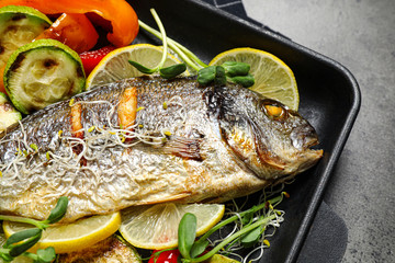 Delicious roasted fish and vegetables on grey table, closeup view