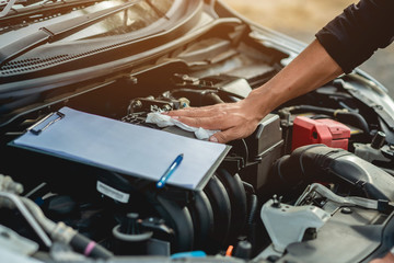 Fototapeta premium The car mechanic is checking the condition of the car and is using the cloth to wipe the engine.