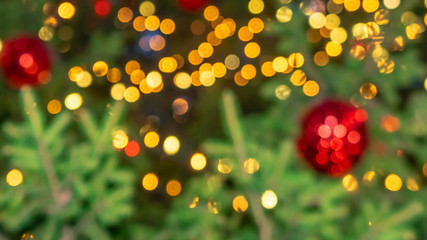 Blurred background of Christmas tree decorated with bright golden lights. Bokeh. Texture of new year fir, toys, illumination. Space for text. Gift postcard. Wallpaper. Banner. Header. 