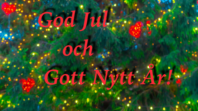 Greetings in Swedish. Christmas and New Year wishes in red letters "God jul och gott nytt ar". Blurred background of Christmas tree decorated with bright golden lights, toys, illumination. Bokeh. 